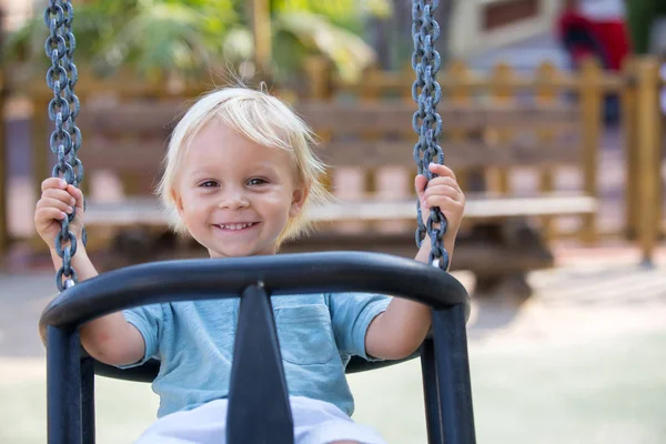Menino pequeno, brincando no playground verão, swingi — Fotografia de Stock