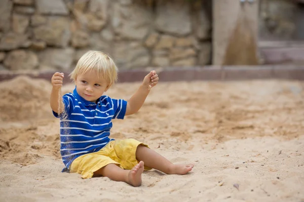 Piccolo bambino, che gioca con la sabbia nella sabbiera del playgrou — Foto Stock