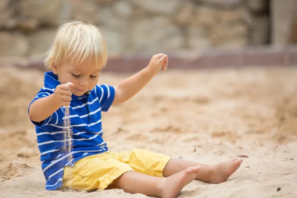 Pequeño niño, jugando con arena en arenero en el playgrou — Foto de Stock