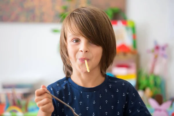 Dulce niño preescolar, comiendo espaguetis en casa, haciendo un lío y —  Fotos de Stock