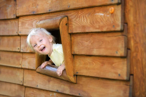 Nieuwsgierig kind, peuter jongen, starend vanuit een klein raam in hout — Stockfoto