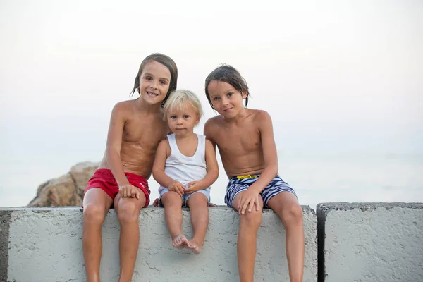 Niños, sentados en la playa, observando barcos iluminados en el océano — Foto de Stock