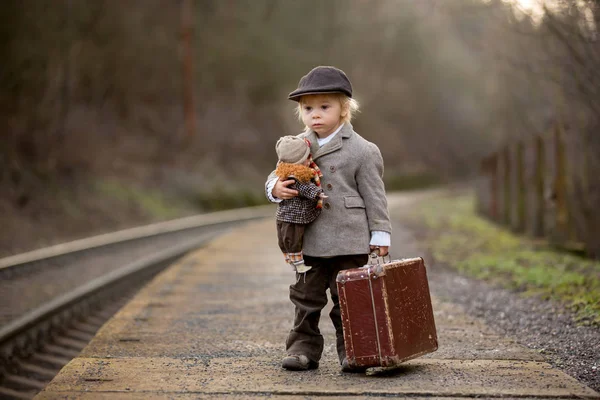 Adorable niño en una estación de tren, esperando el tren con su —  Fotos de Stock