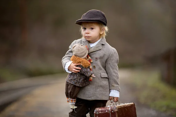 Adorabile ragazzo su una stazione ferroviaria, in attesa del treno con su — Foto Stock