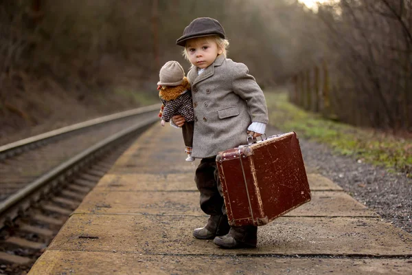 Förtjusande pojke på en järnvägsstation, väntar på tåget med su — Stockfoto