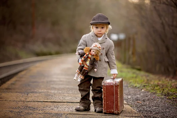 Adorable niño en una estación de tren, esperando el tren con su — Foto de Stock