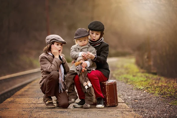 Adorables chicos en una estación de tren, esperando el tren con s — Foto de Stock