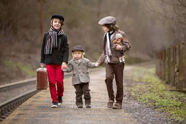 Ragazzi adorabili su una stazione ferroviaria, in attesa del treno con s — Foto Stock