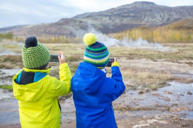 Çocuklar, patlama sırasında Strokkur Geysir 'in fotoğrafını çekiyor, Icel