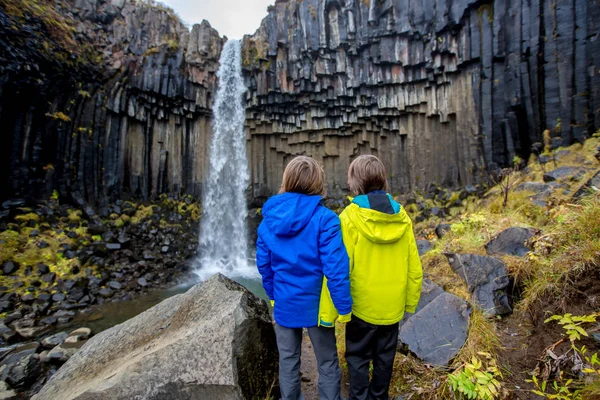 Šťastné dítě, pózování před krásným vodopádem Svartifoss i — Stock fotografie