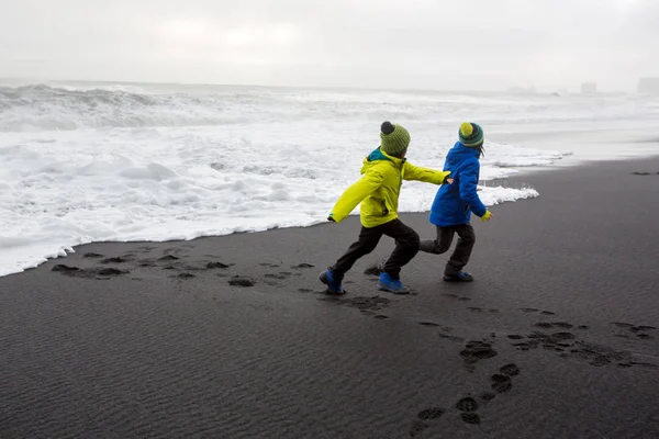 Kinderen van en naar de oceaan in het zwarte zandstrand van Re — Stockfoto