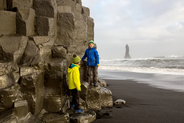 Crianças, meninos irmãos, posando na rocha da praia de areia preta o — Fotografia de Stock