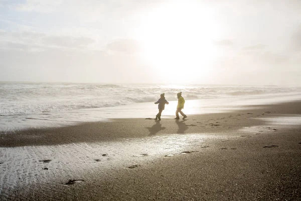 在Re的黑色沙滩上，孩子们从大海中跑来跑去 — 图库照片