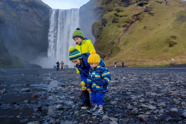 Criança bonita brincando na frente da cachoeira Skogafoss em islandês — Fotografia de Stock