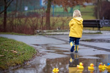Beautiful funny blonde toddler boy with rubber ducks and colorfu