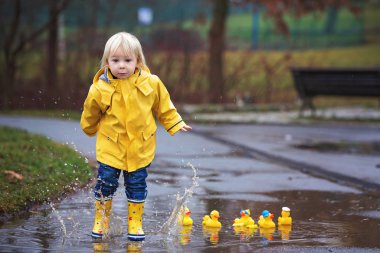 Beautiful funny blonde toddler boy with rubber ducks and colorfu