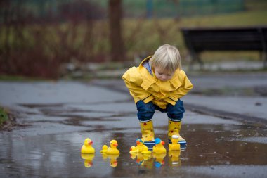 Beautiful funny blonde toddler boy with rubber ducks and colorfu