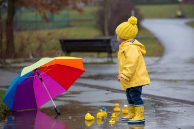 Beautiful funny blonde toddler boy with rubber ducks and colorfu