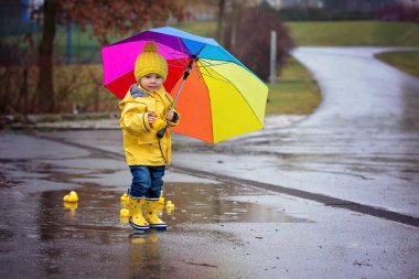 Beautiful funny blonde toddler boy with rubber ducks and colorfu