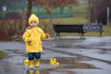 Beautiful funny blonde toddler boy with rubber ducks and colorfu