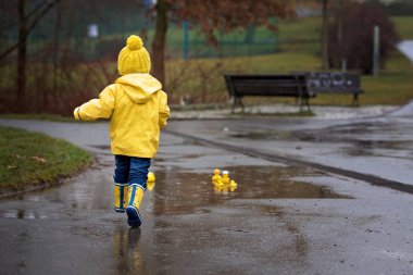 Beautiful funny blonde toddler boy with rubber ducks and colorfu