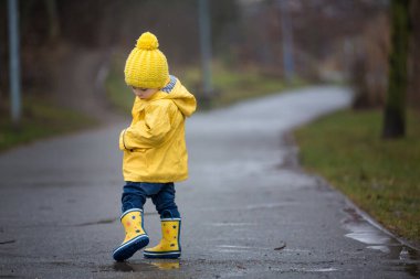 Beautiful funny blonde toddler boy with rubber ducks and colorfu