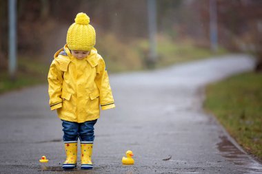 Beautiful funny blonde toddler boy with rubber ducks and colorfu