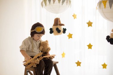 Sweet toddler boy, playing with airplane and teddy bear, air bal