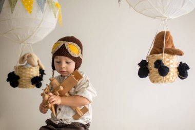 Sweet toddler boy, playing with airplane and teddy bear, air bal