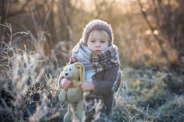 Şapkası ve şapkası olan, örgülü bir elbise giymiş, güzel bir çocuk.