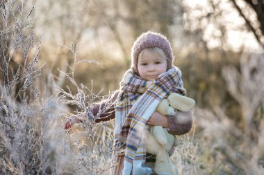 Şapkası ve şapkası olan, örgülü bir elbise giymiş, güzel bir çocuk.