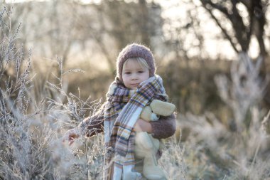 Şapkası ve şapkası olan, örgülü bir elbise giymiş, güzel bir çocuk.