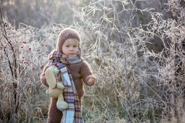 Şapkası ve şapkası olan, örgülü bir elbise giymiş, güzel bir çocuk.
