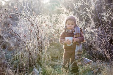Şapkası ve şapkası olan, örgülü bir elbise giymiş, güzel bir çocuk.