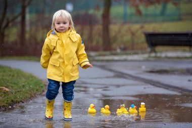Beautiful funny blonde toddler boy with rubber ducks and colorfu