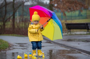 Beautiful funny blonde toddler boy with rubber ducks and colorfu