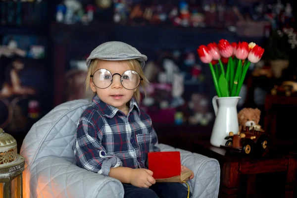 Dulce niño, con gafas, leyendo un libro y bebiendo —  Fotos de Stock