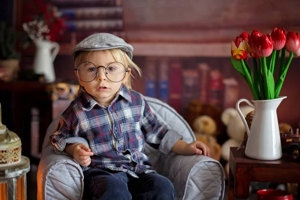 Dulce niño, con gafas, leyendo un libro y bebiendo — Foto de Stock