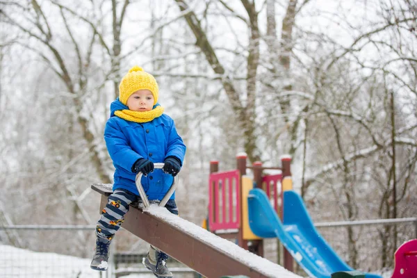 Lieve peuter jongen, spelen met sneeuw op de speelplaats — Stockfoto