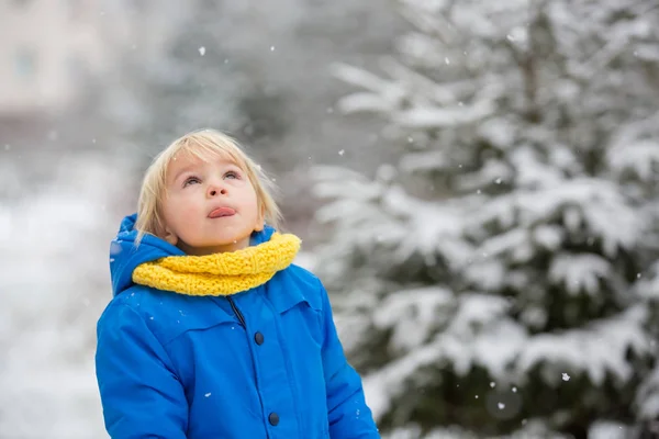 Солодкий хлопчик-малюк, грає зі снігом на дитячому майданчику — стокове фото