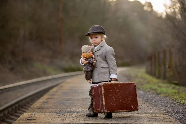 Adorable niño en una estación de tren, esperando el tren con su —  Fotos de Stock