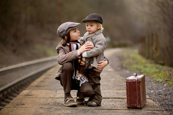 Roztomilí chlapci na nádraží, čeká na vlak s — Stock fotografie