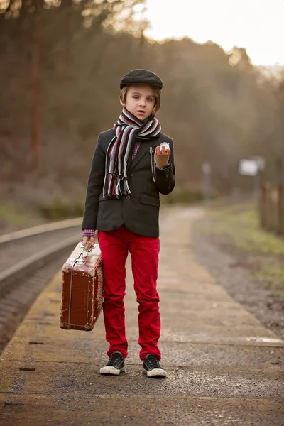 Adorable garçon sur une gare, attendant le train avec su — Photo