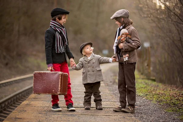 Adorables chicos en una estación de tren, esperando el tren con s —  Fotos de Stock