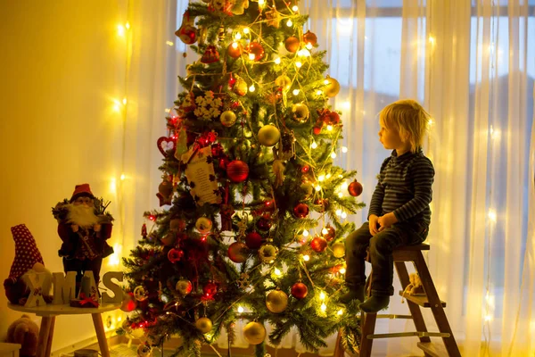 Gyönyörű szőke kisgyerek fiú, díszítő karácsonyfa bal — Stock Fotó