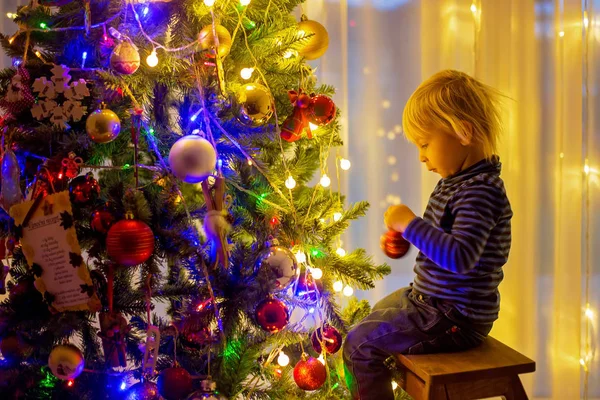 Hermoso niño rubio, decorando el árbol de Navidad con bal —  Fotos de Stock