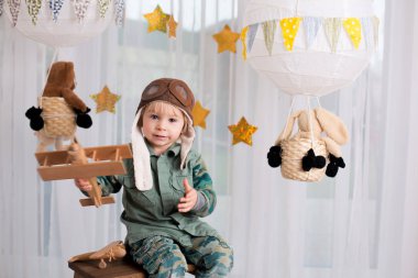 Sweet toddler boy, playing with airplane and teddy bear, air bal
