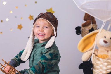 Sweet toddler boy, playing with airplane and teddy bear, air bal