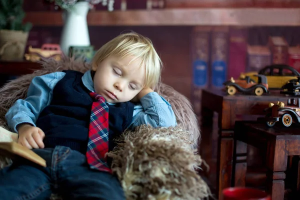 Menino da criança doce, adormecer no pequeno sofá do bebê enquanto lê — Fotografia de Stock