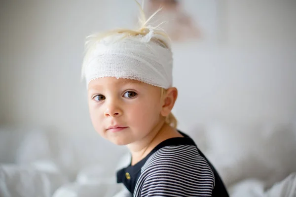 Close portrait of little toddler boy with head injury, sitting i — Stock Photo, Image